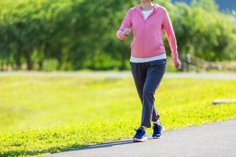 スポーティなウェアを着てウォーキングをする女性の写真。首から下が写っている。